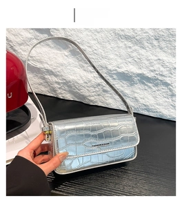 Detail der silbernen Schultertasche mit Kroko-Prägung und modischem Metall-Schriftzug