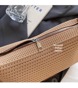 Dettaglio macro della cerniera in metallo su borsa a tracolla intrecciata beige di lusso