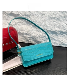 Detail der blauen Schultertasche mit Krokodilmuster und goldenem FASHION & BAGS Logo