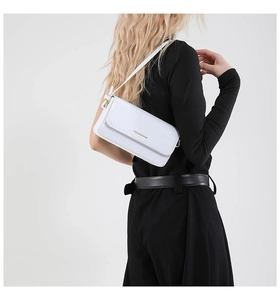 Close-up of white croc-effect shoulder bag with gold logo and elegant metal hardware