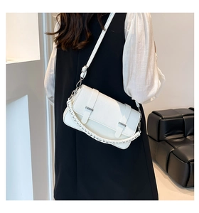 Detail of white crocodile embossed leather bag with dual straps and flip-lock hardware