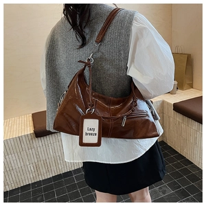 Detail of dark brown glossy leather hobo bag with silver zipper and Lazy Breeze tag