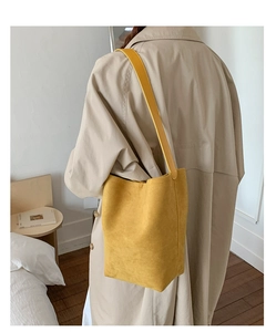 Chic mustard yellow suede bucket bag worn by model over a classic autumn trench coat