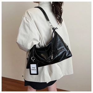 Close-up of black textured leather hobo bag with knotted strap and metal ring detail