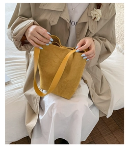 Detail of ginger yellow matte leather bucket bag showing soft suede texture and minimal design