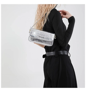 Detailaufnahme der silbernen Schultertasche mit Krokodilprägung und Metallic-Oberfläche