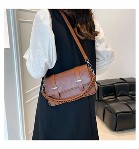 Detail einer braunen Handtasche mit Flechtstruktur, Silberbeschlägen und Tragegriff