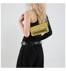 Nahaufnahme der goldenen Kroko-Handtasche mit eleganter Metallkette und modischem Logo