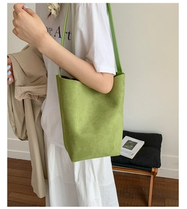 Detail of a minimalist green suede bucket bag showing matte texture and clean strap lines