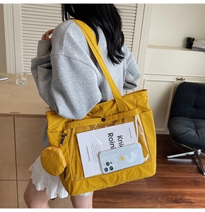 Detail of yellow canvas tote bag featuring clear PVC front pocket and mini round pouch