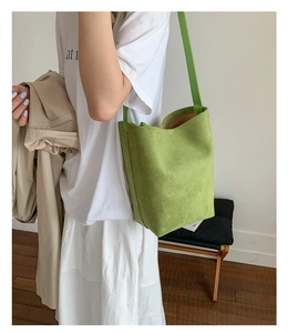 Detail of the grass green suede bucket bag showing rich texture and adjustable shoulder strap
