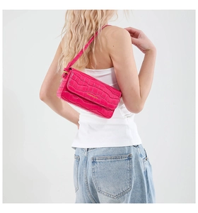 Detail of fuchsia crocodile embossed faux leather shoulder bag with gold logo on flap