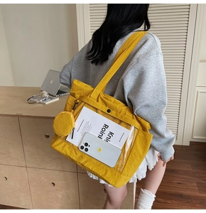 Detail of yellow canvas tote bag with transparent front pocket and mini coin purse charm