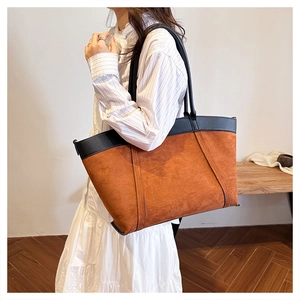 Detalle de bolso tote de ante vintage con ribete de cuero y correas largas al hombro