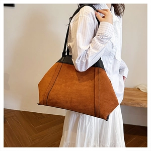 Detalle de bolso tote de ante marrón con correas de cuero negro puesto en modelo
