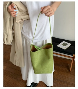 Detail of lime green frosted suede bucket bag with fine stitching on model's outfit