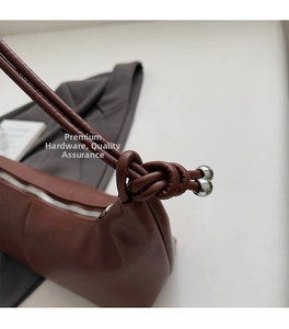 Detail of dark brown leather handbag with knotted shoulder strap and silver metal beads