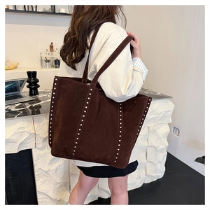 Detail of dark brown suede tote bag with silver studs and long shoulder straps