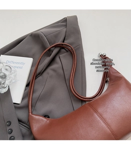 Close-up of brown leather hobo bag with knotted shoulder strap and metal bead detail