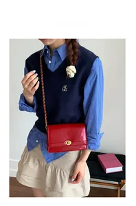 Close-up of red patent leather crossbody bag with gold twist lock and chain strap