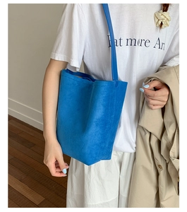 Detail of blue suede minimalist tote bag with thin strap worn over the shoulder