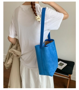 Detail of Klein blue matte suede tote bag worn on shoulder in minimalist setting