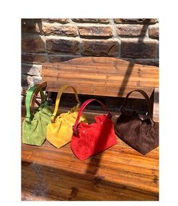 Four colorful frosted PU bucket bags with cloud pleats on a vintage wooden bench