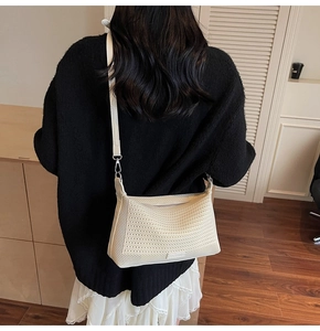 Dettaglio di una borsa a tracolla beige in rete intrecciata con sottile cinturino in pelle