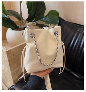 Close-up of cream leather bucket bag with silver chain strap and drawstring detail