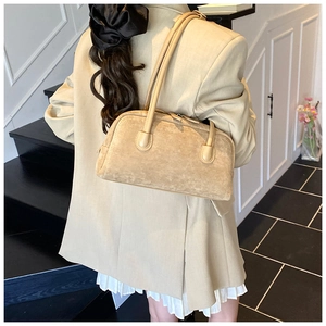 Chic beige suede baguette bag styled as an underarm shoulder bag on a model