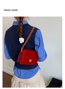 Model view of a red leather crossbody square bag with gold chain strap and metal lock