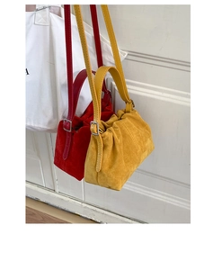 Detail of red and yellow suede pleated handbags with adjustable silver buckles and straps
