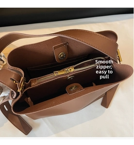 Interior detail of caramel bucket bag showing central zipper and magnetic buckles