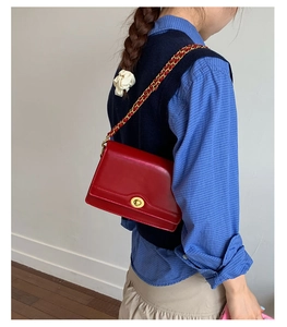 Detail of red glossy shoulder bag with vintage gold metal twist lock and chain strap