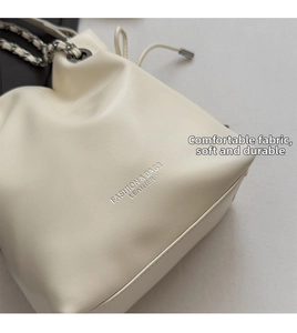 Detail of creamy white drawstring bucket bag with silver chain and smooth leather texture