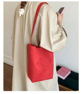 Detailed back view of a large red matte bucket bag worn over a beige coat