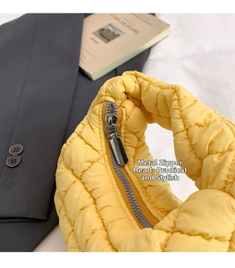 Detail of bright yellow quilted bag featuring a durable polished silver metal zipper puller