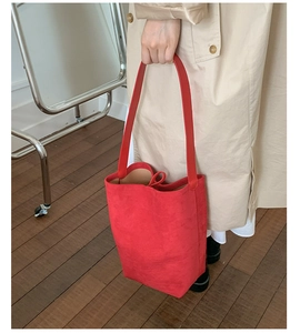 Detailed close-up of a red suede bucket bag featuring long straps and soft matte texture
