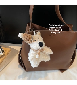Close-up of brown leather tote bag detail with a cute white plush bear charm accessory