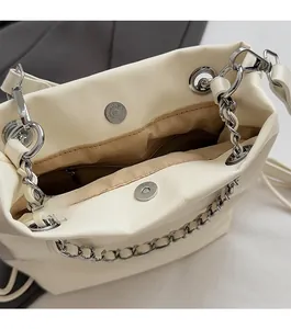 Detail view of large cream chain bag featuring magnetic closure and inner zipper pocket