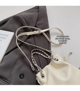 Close-up of cream bucket bag with silver chain handles and adjustable leather shoulder strap