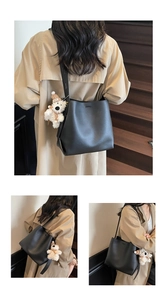 Detail showing a black leather bucket bag with a cute plush bear charm on a model