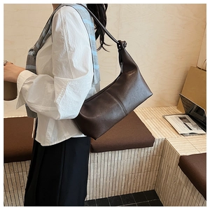 Detail of vintage brown leather dumpling bag with knotted strap and soft grainy texture
