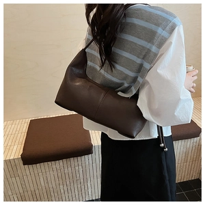 Side view of dark brown leather underarm bag with vertical seam detail on model