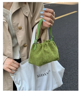 Detail of green suede pleated dumpling bag with drawstring and adjustable leather strap