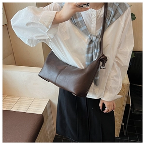 Detail of brown crescent bag with vertical stitching and knotted strap decoration