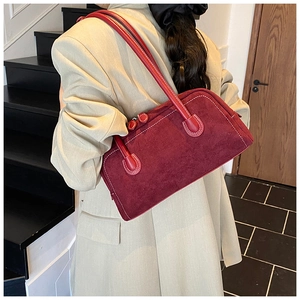 Detail view of burgundy baguette bag featuring white contrast stitching on suede leather