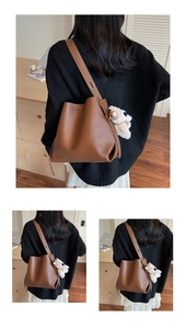 Detailed view of a brown leather bucket bag with a cute white plush bear pendant