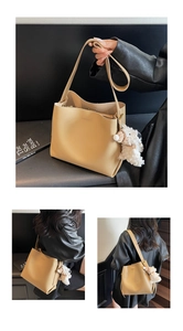 Detail of beige bucket bag with plush puppy charm and interior zip pocket on black bench