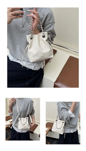 Close-up of beige leather drawstring bucket bag featuring chain strap and silver eyelets